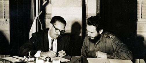 El anodino presidente de Cuba, Dr. Osvaldo Dorticós Torrado, firma el 6 de julio de 1960 la Ley No. 851 de expropiación de propiedades norteamericanas legítimamente establecidas en territorio nacional de La Isla, ante la mirada atenta de Fidel Castro Ruz, a la sazón Primer Ministro del Gobierno Revolucionario Cubano.